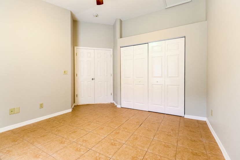 an empty room with a tiled floor and three closet doors