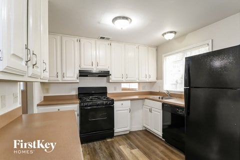 A kitchen with black appliances and white cabinets.