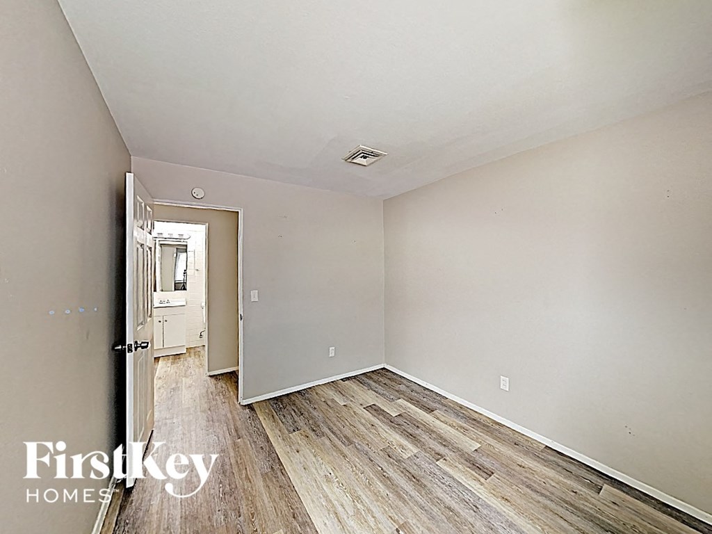 an empty bedroom with wood flooring and white walls