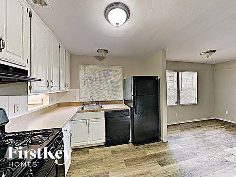 a kitchen with white cabinets and a black refrigerator