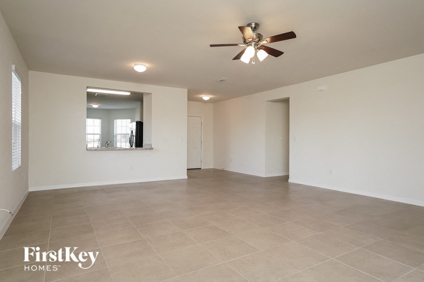 an empty living room with white walls and a ceiling fan