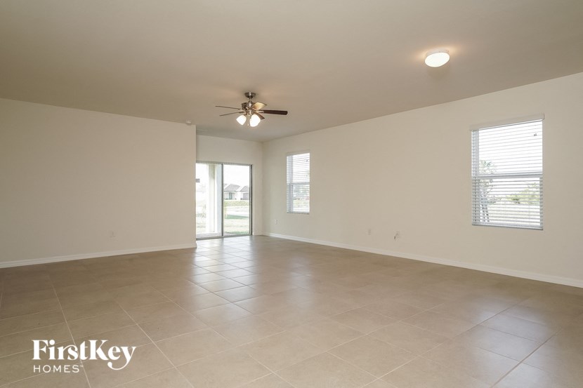 an empty living room with a ceiling fan and tiled floor