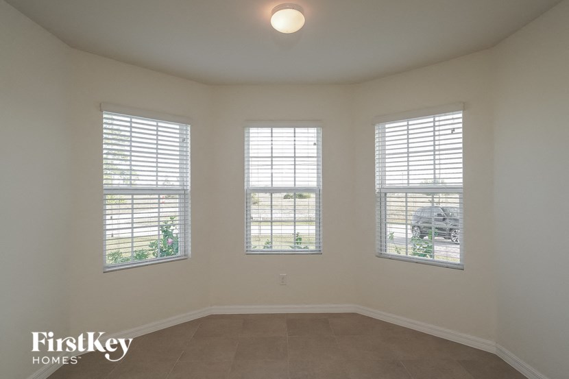 a living room with three windows and a tile floor