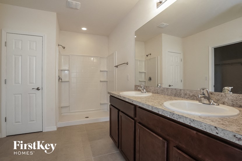 the master bathroom has dual sinks and a large mirror