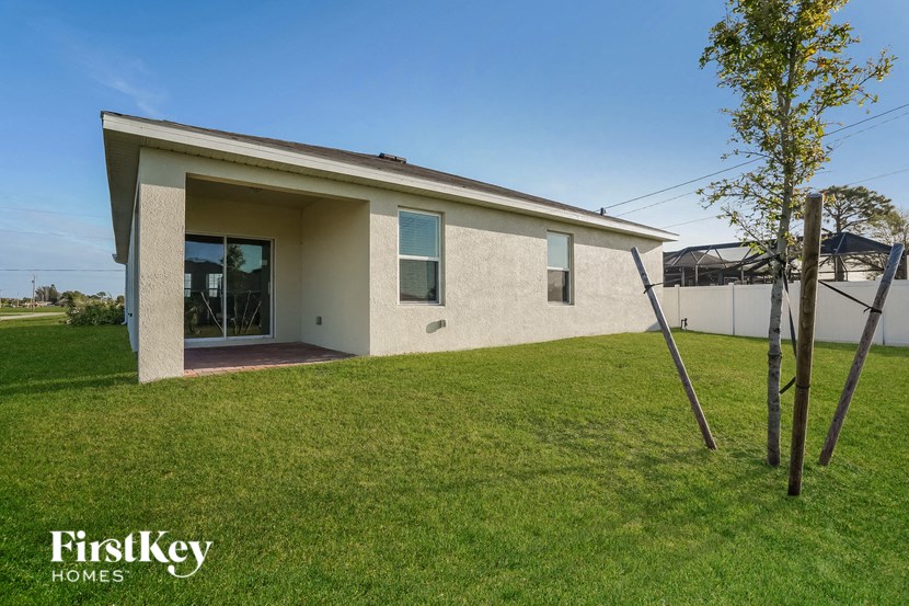a small white house with a lawn and a tree