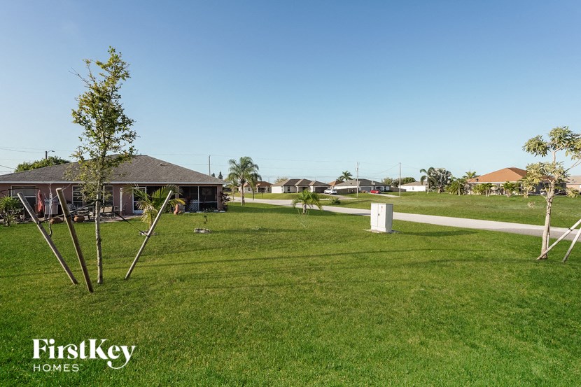 a house in the middle of a field with grass and trees