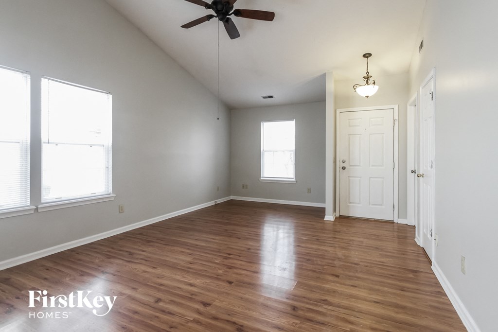 an empty living room with wood floors and a ceiling fan