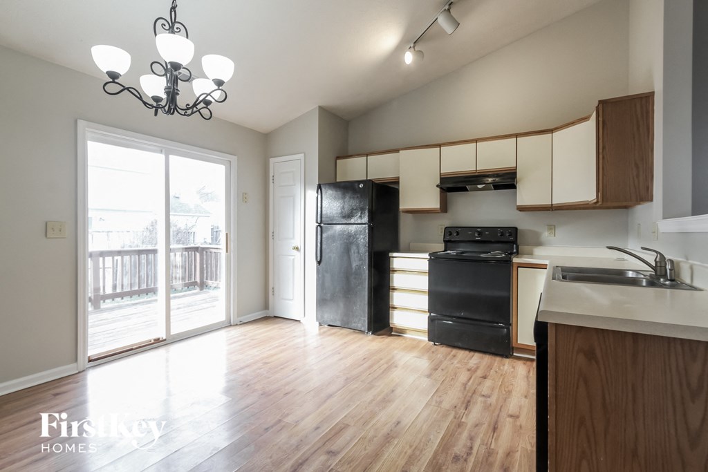 an empty kitchen with black appliances and a sliding glass door