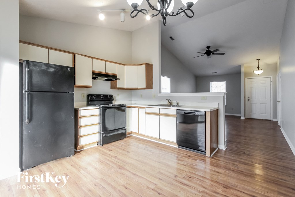 a kitchen with white cabinets and black appliances and a wood floor