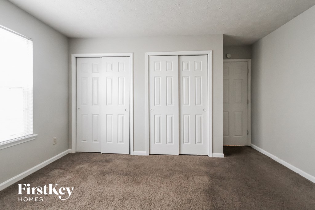 a bedroom with three doors and a carpeted floor