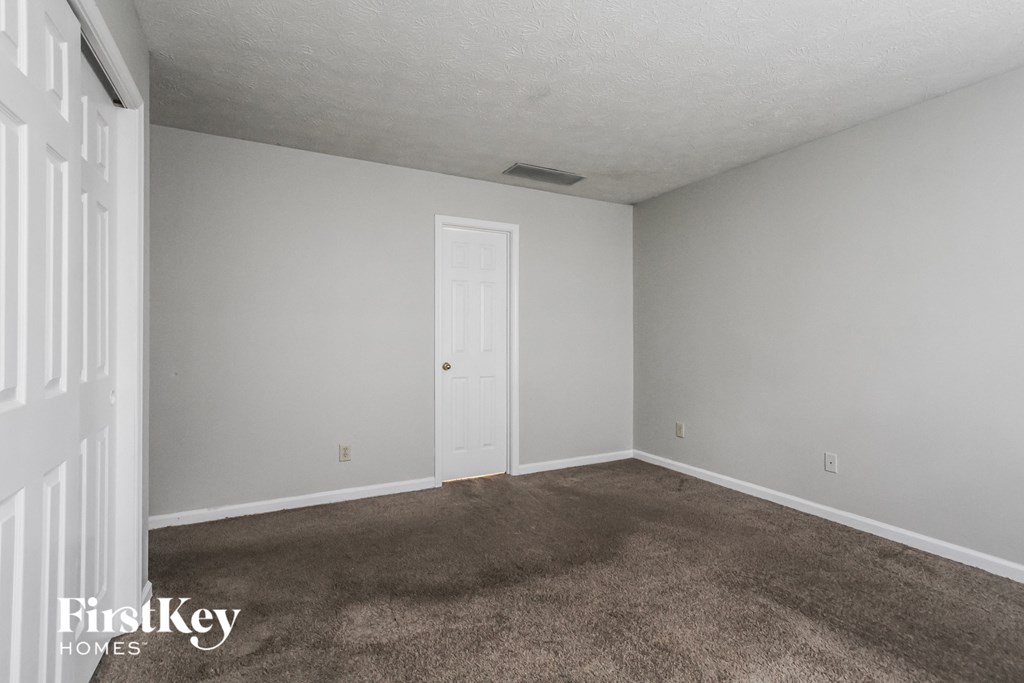 a bedroom with a carpeted floor and a white door