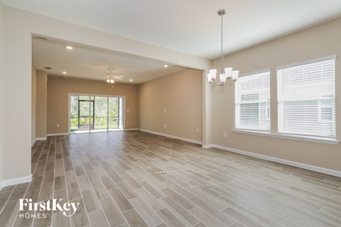A spacious room with wooden flooring and a chandelier hanging from the ceiling.