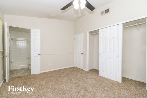 A bedroom with a carpeted floor and a ceiling fan.
