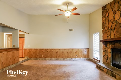 A living room with a fireplace and a ceiling fan.