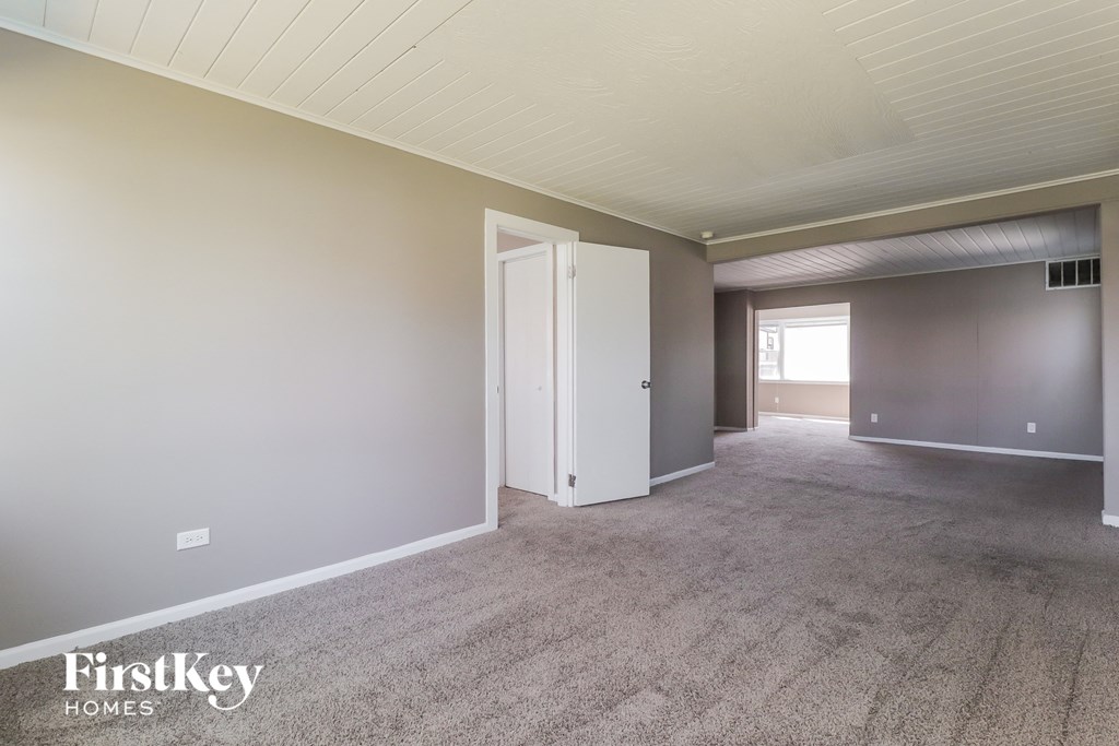 A room with a carpeted floor and a door leading to another room.