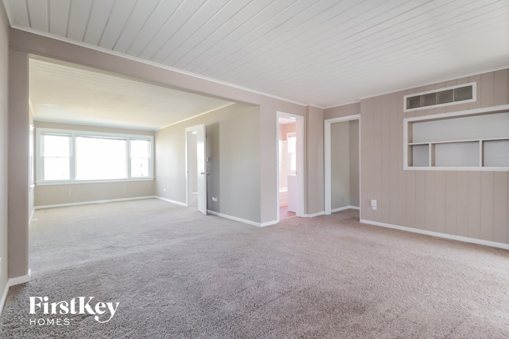A spacious room with a carpeted floor and a window letting in natural light.