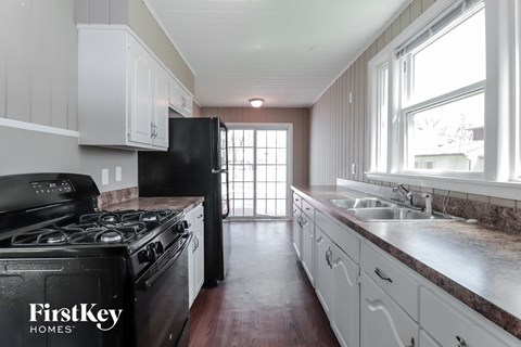 A kitchen with a black stove top oven and a black refrigerator.