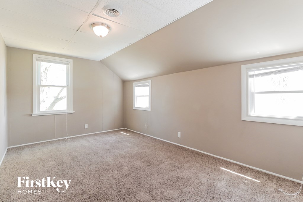 A room with a carpet floor and two windows.