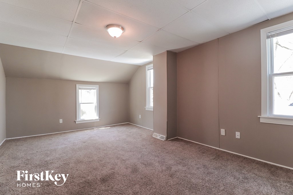 A room with a carpeted floor and two windows.