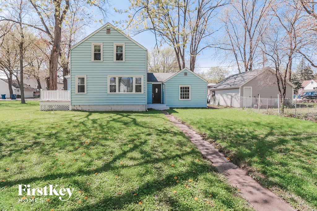 A blue house with a white fence and a green lawn in front.