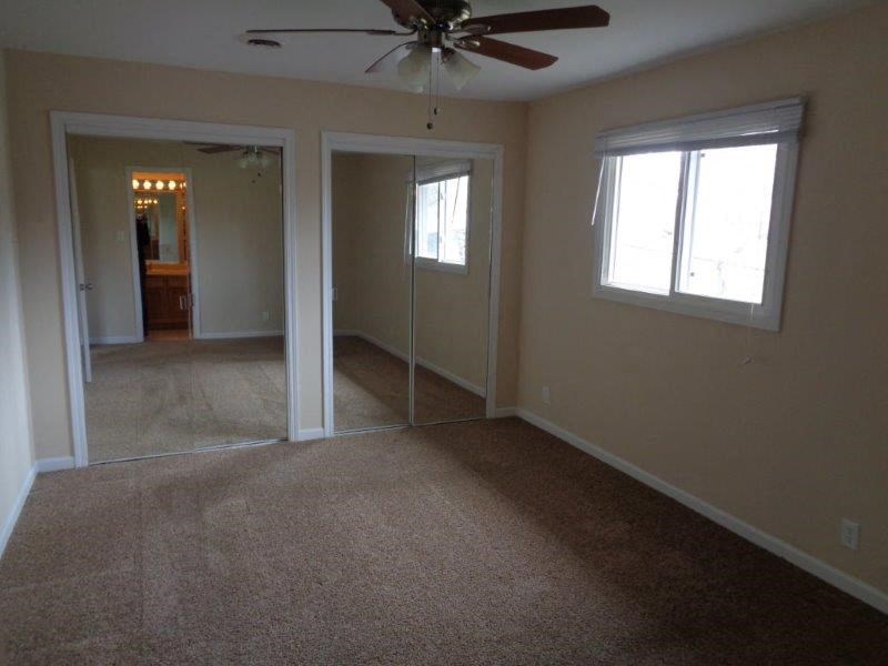 an empty living room with a ceiling fan