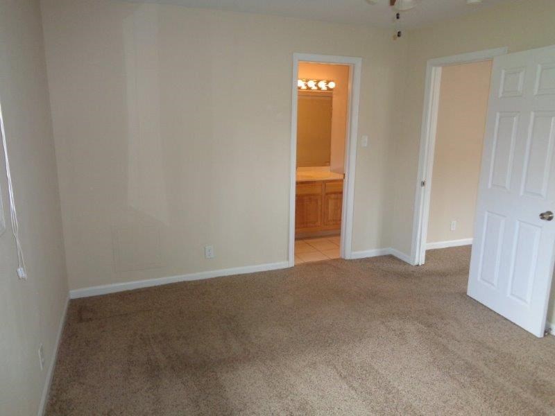 an empty living room with a door to a bathroom
