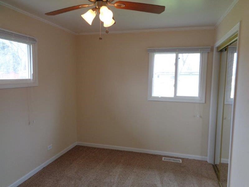 an empty room with a ceiling fan and two windows