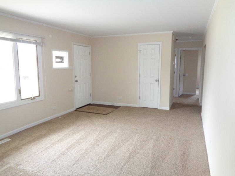 an empty living room with two doors and a carpet