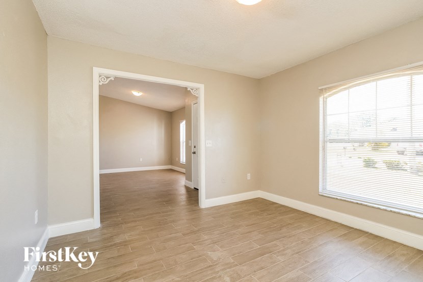 an empty living room with a large window and wood flooring