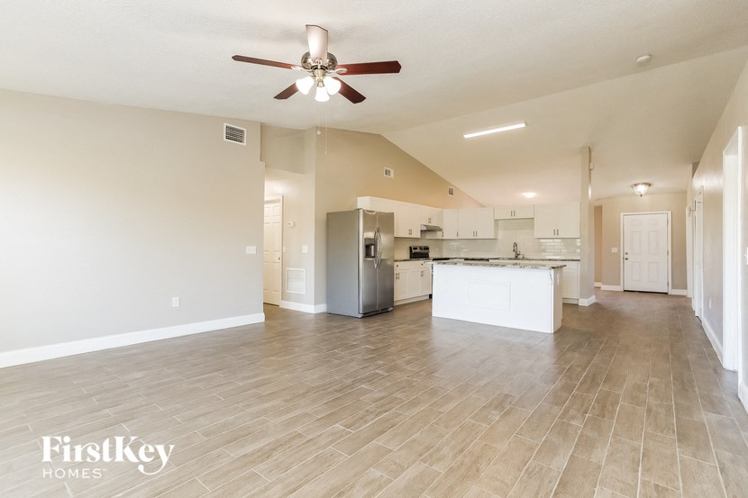 an empty living room and kitchen with a ceiling fan