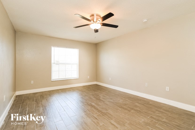 an empty living room with a ceiling fan and a window