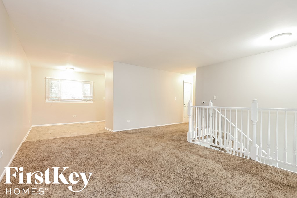 A spacious room with a carpeted floor and white railings.