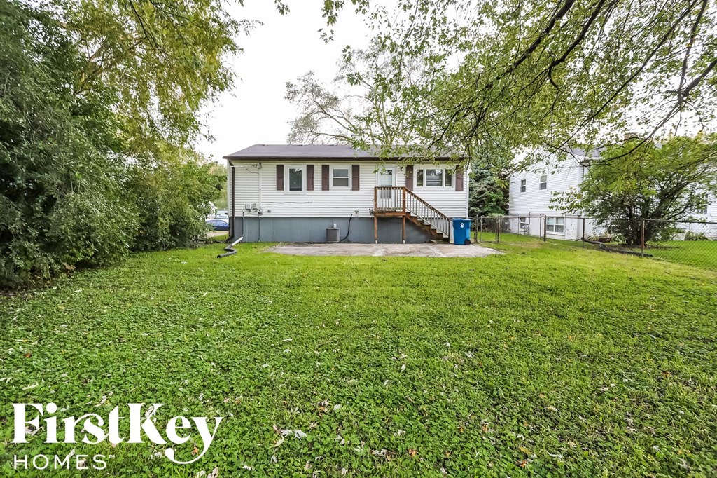 A house with a lawn and trees in the background is for sale.