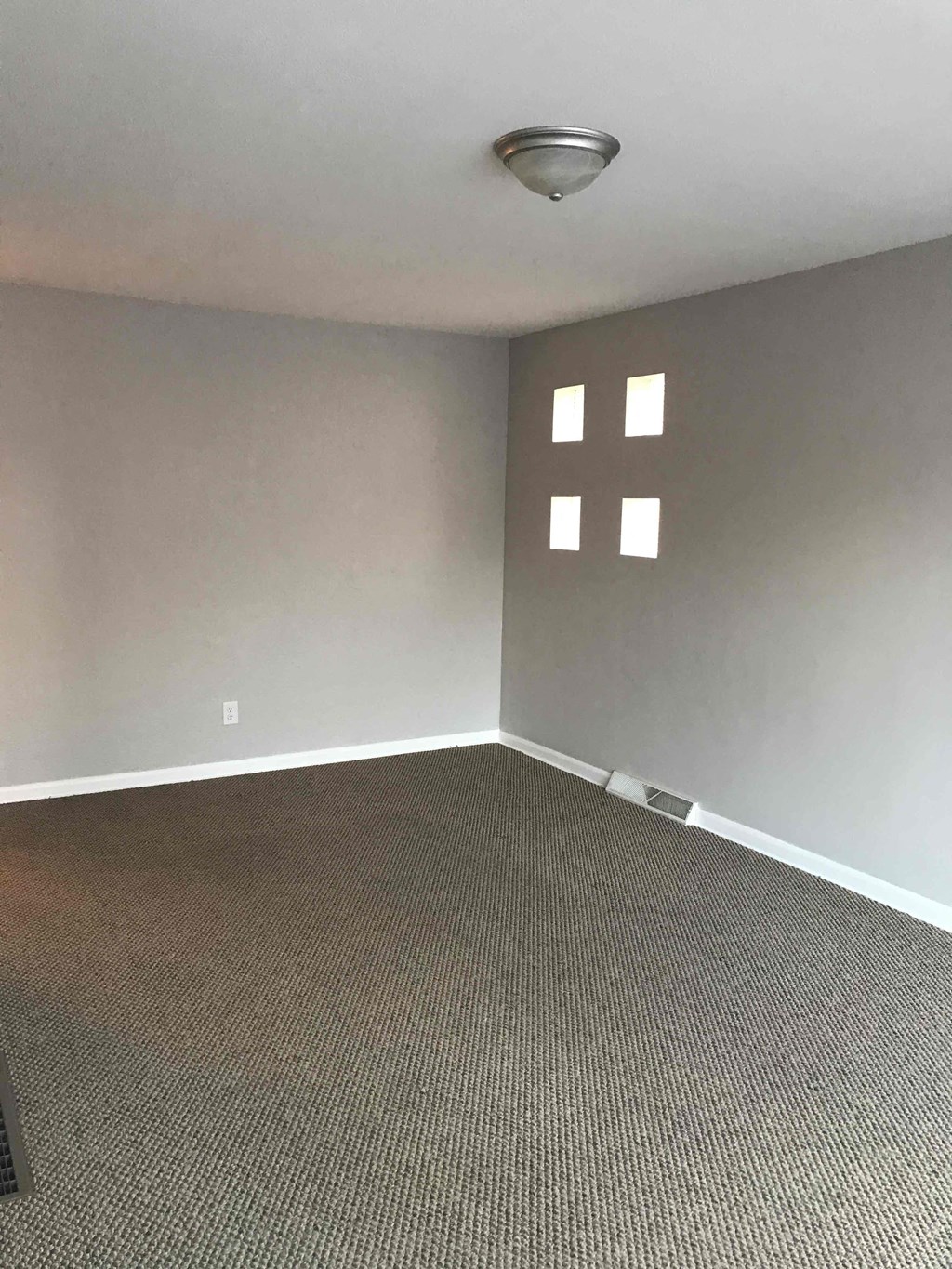 an empty room with a carpet and two windows