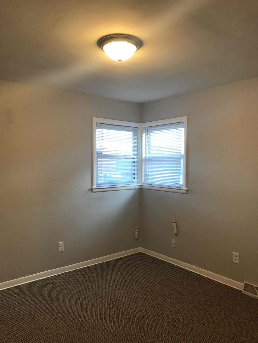 an empty room with a window and a light on the ceiling