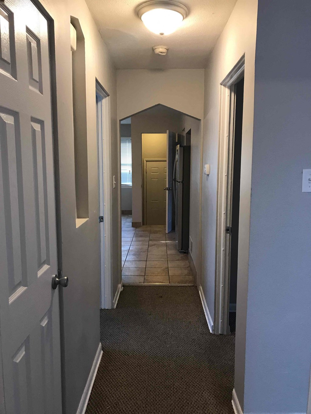 a hallway with a door open and a tiled floor