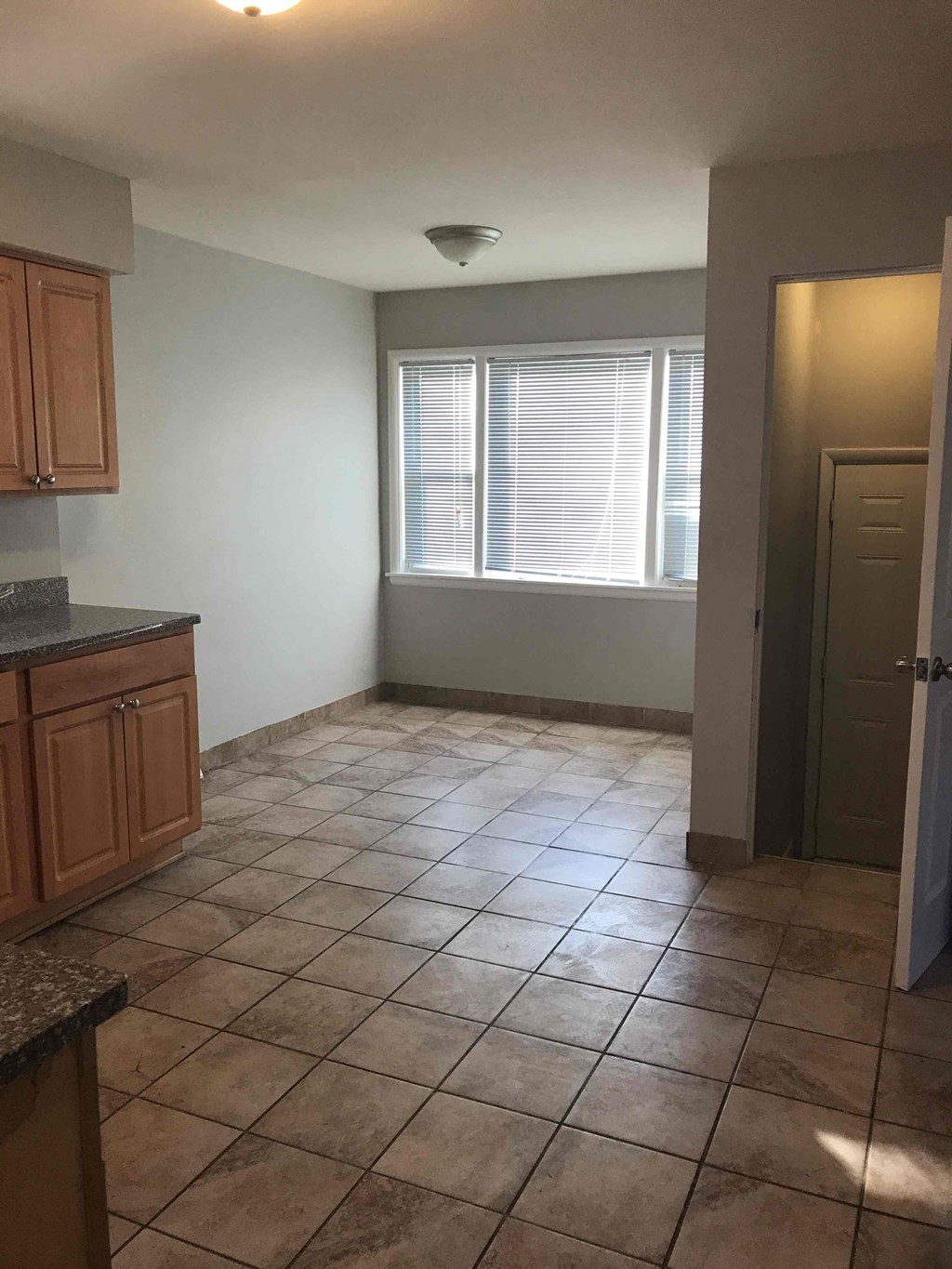 an empty kitchen with tile flooring and a window