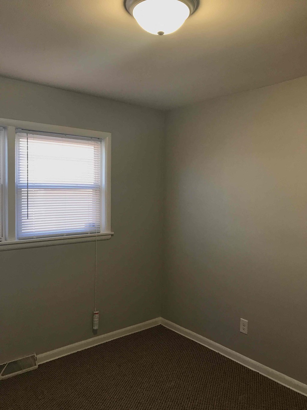 an empty room with a window and a lamp