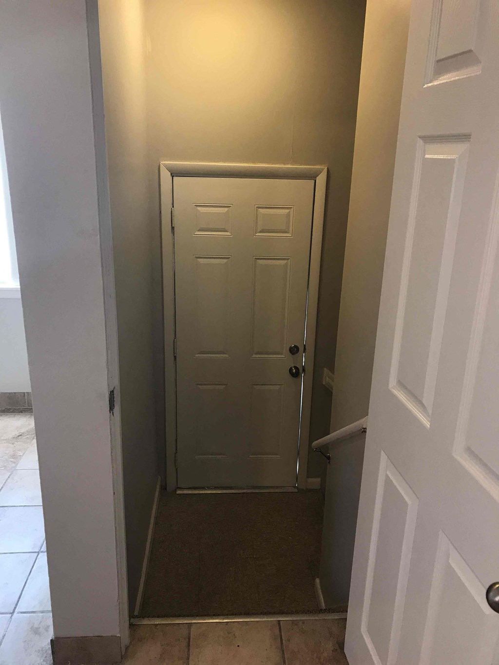 a hallway with a white door and a carpeted floor