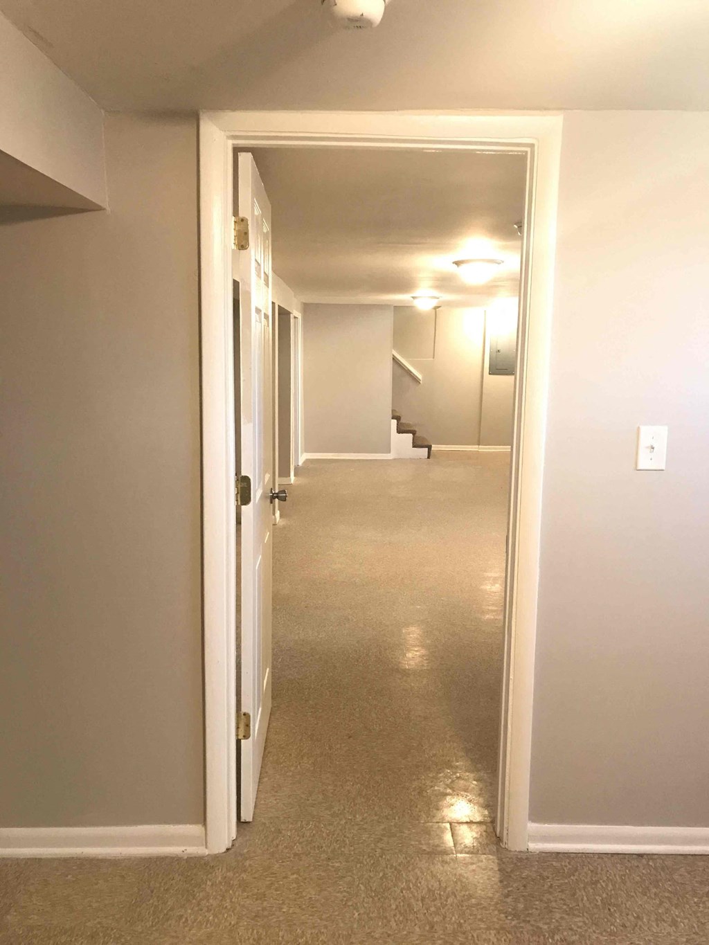 a hallway with a hallway door open to a living room and stairs