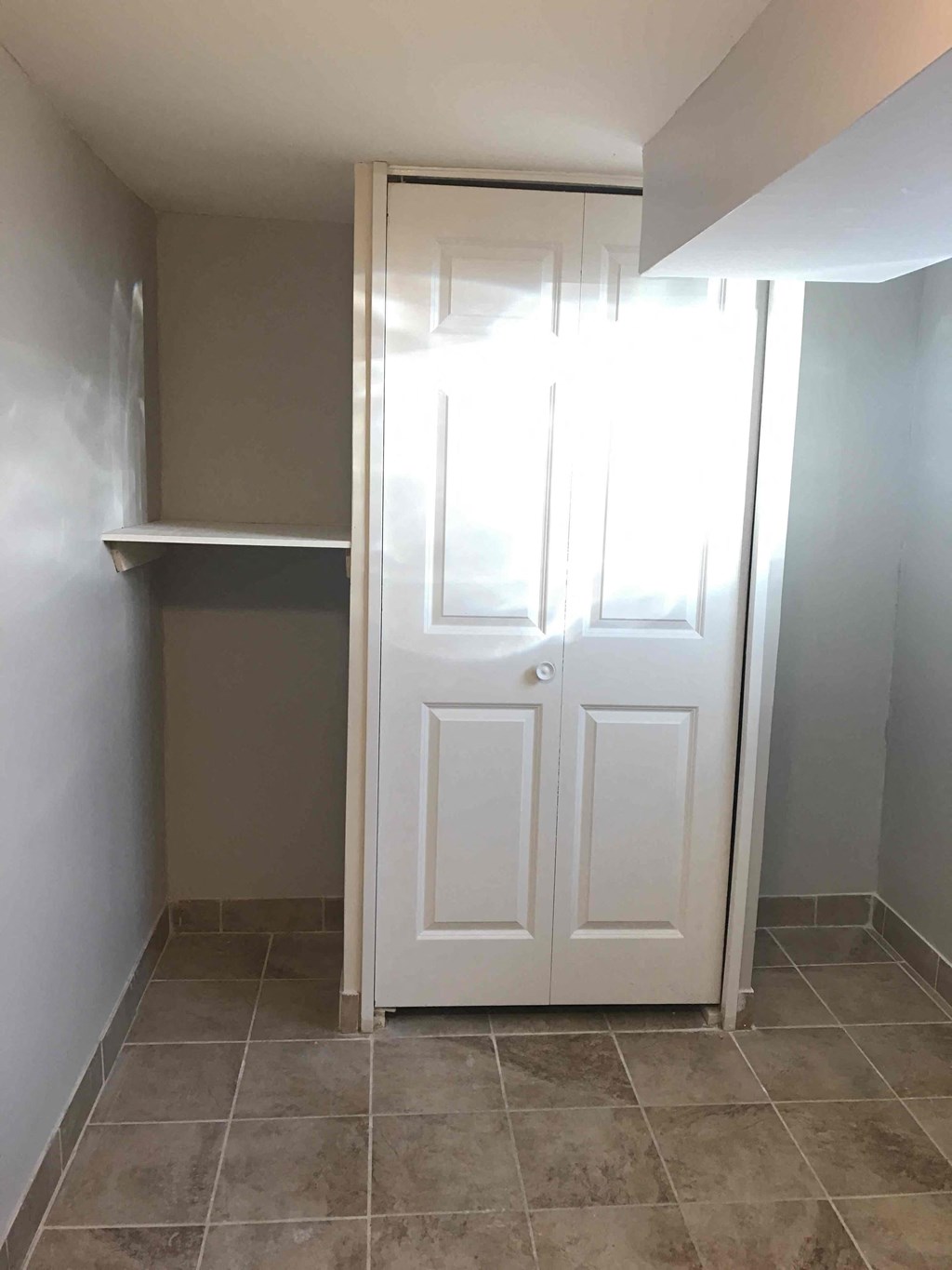 a closet with a white door and a shelf
