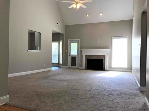 A spacious living room with a fireplace and a ceiling fan.