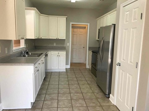A kitchen with white cabinets and a tile floor.