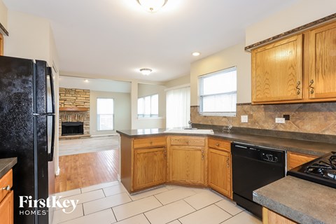 A kitchen with wooden cabinets and a black fridge.