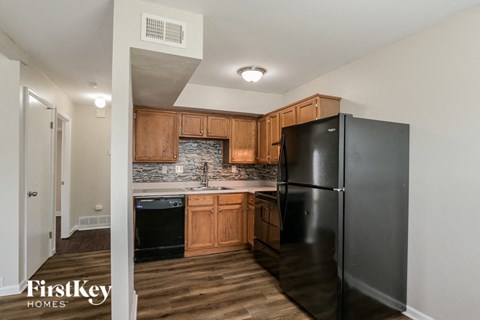 a kitchen with black appliances and wooden cabinets and a black refrigerator