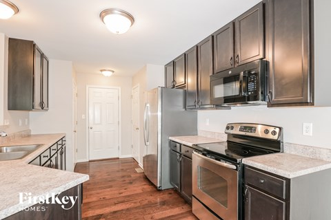 a kitchen with stainless steel appliances and black cabinets and white counter tops