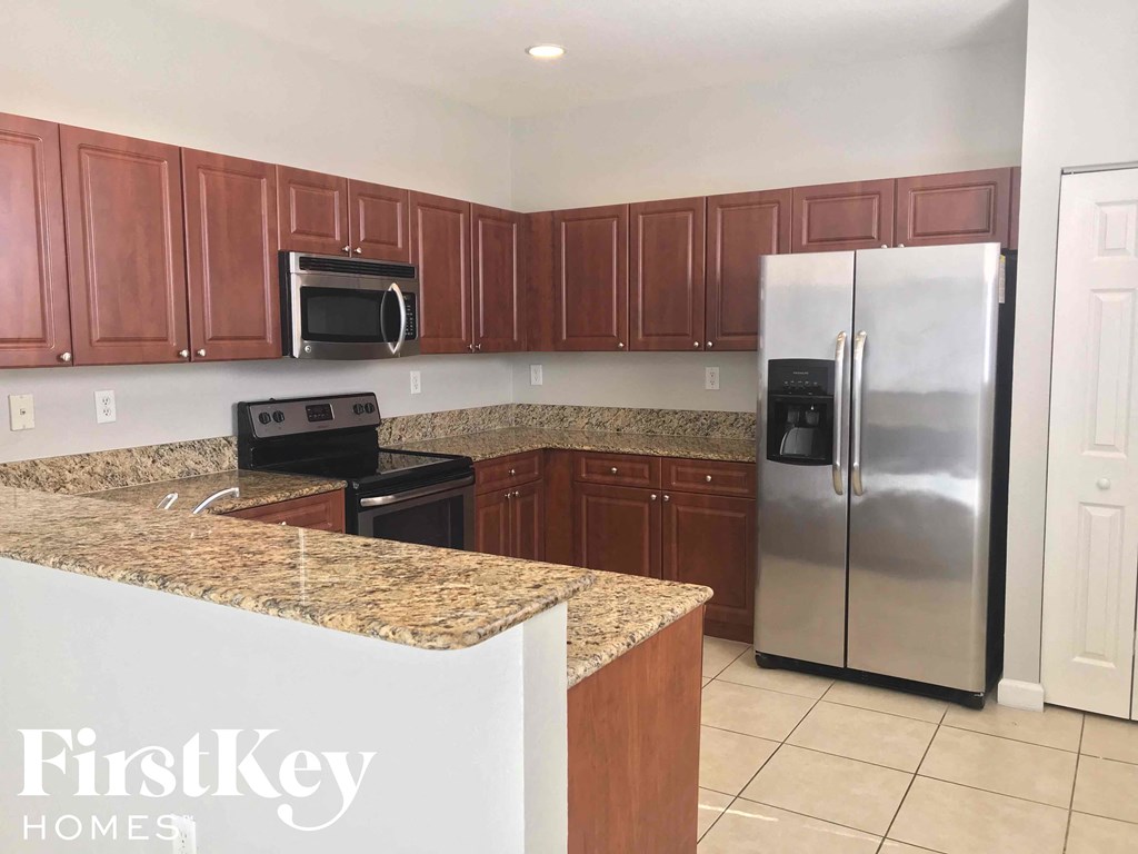 A kitchen with a refrigerator, microwave, and oven.