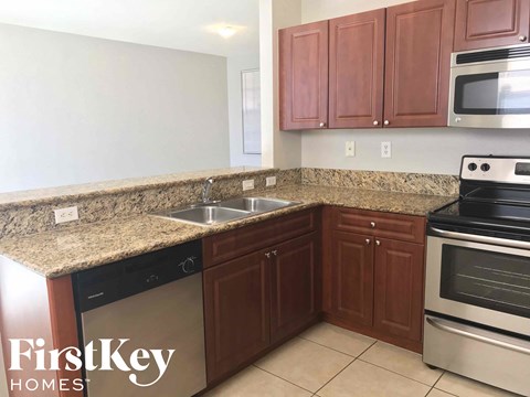 A kitchen with brown cabinets and granite countertops.