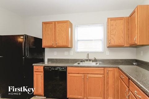 A kitchen with wooden cabinets and a black refrigerator.