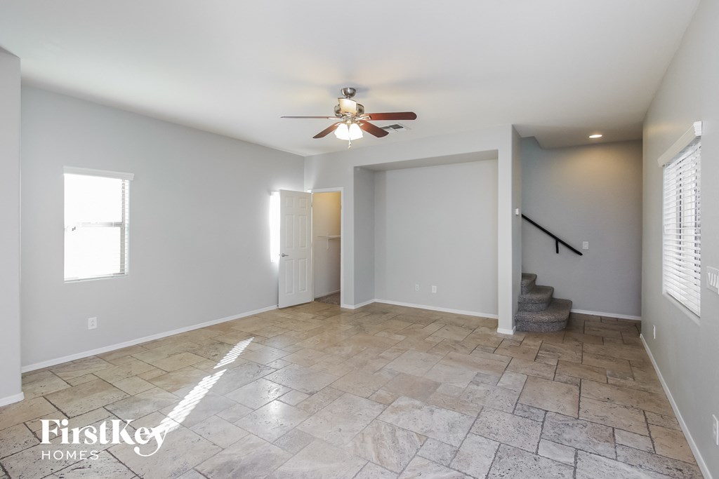 an empty living room with a ceiling fan and a staircase